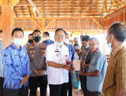 Bupati Pesisir Barat DR. Drs. Agus Istiqlal, S.H.,M.H Menyerahkan Buku Tabungan Kepada Warga Pemilik Tanah Bangunan